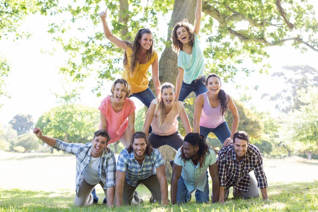 Happy Friends In The Park Making Human Pyramid On A Sunny Day