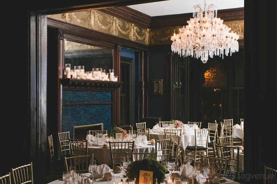 Masquerade Holiday Ball: crystal chandelier above white-linen banquet tables in the Venetian-Gothic ballroom at Montauk Club, Brooklyn