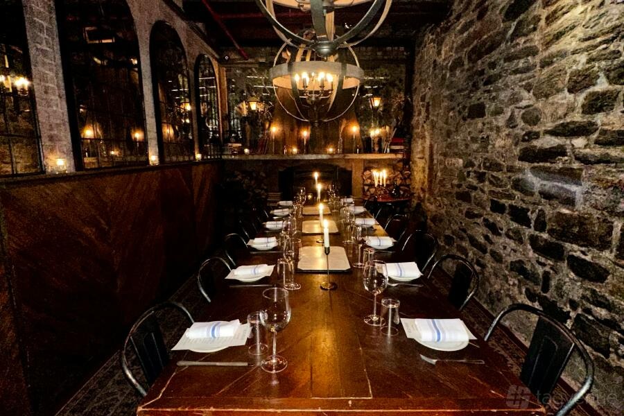 Candlelit Christmas: one long candlelit table against exposed stone in The Uva Room at Gelso & Grand, New York City