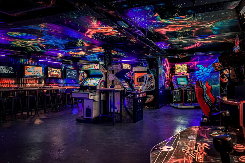 Dark arcade with retro games and colourful lights on the ceiling