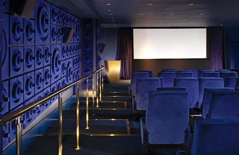 Dark blue elegant cinema room with gold detailing.
