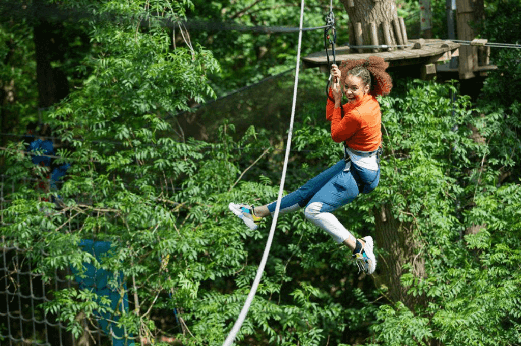 a woman screaming with excitement on a zip line in a forest