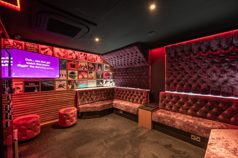 Red karaoke lounge with plush seats and dimmed lights.