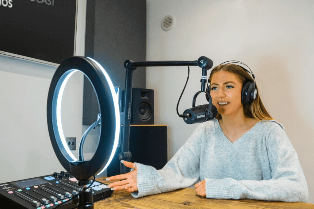 A smiling woman recording a podcast in a professional stduio