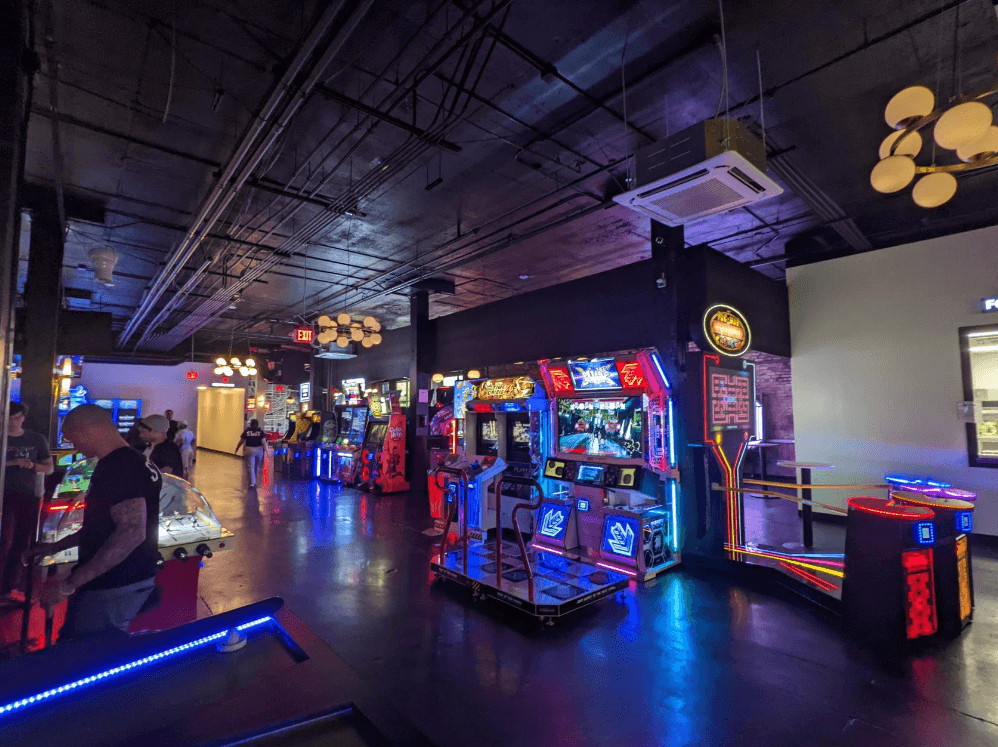 A dark venue lit up by colourful arcade games