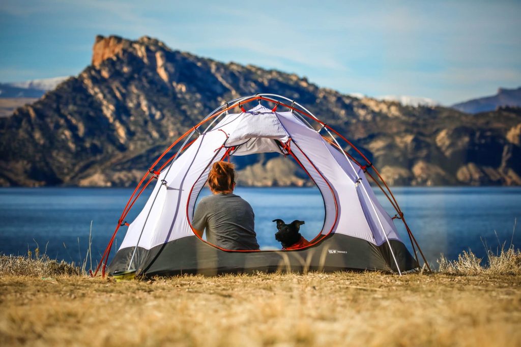 A woman with a dog in a tent, looking at the lake