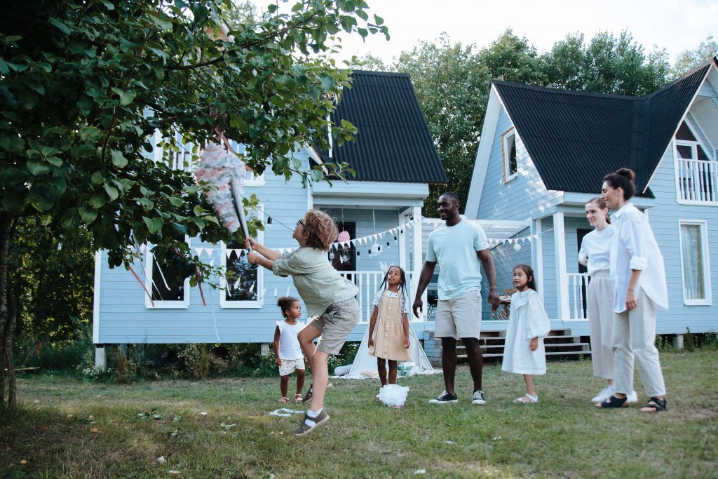 people of differentr ages playing piñata in the backyard