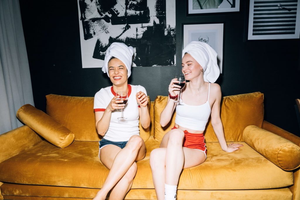 two women drinking wine on a couch 