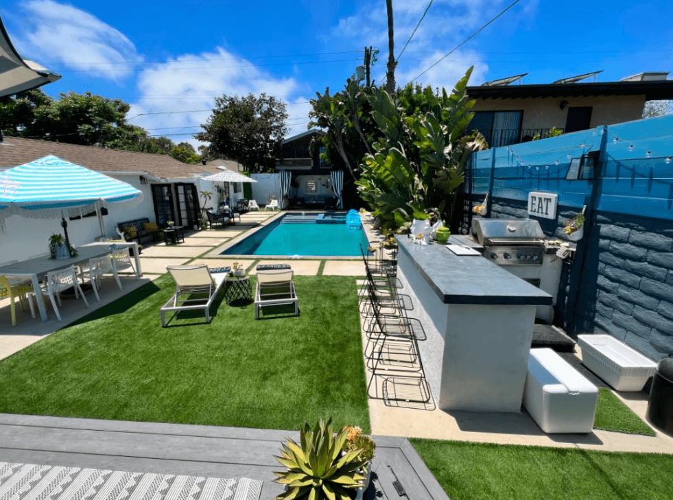 A house backyard with swimming pool, chairs, and a bar