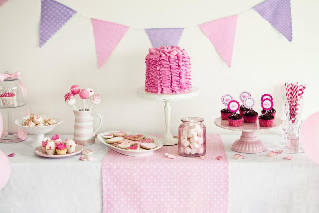 A buffet table with various types of candy on display, such as cupcakes, cookies, and lollipops.