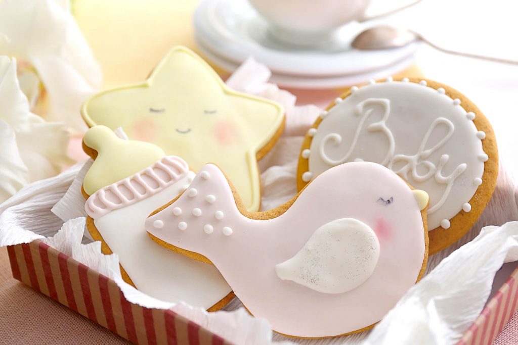 A tray with cookies shaped like a bird, a baby bottle, a star with a smiling face, and one round cookie with the word 