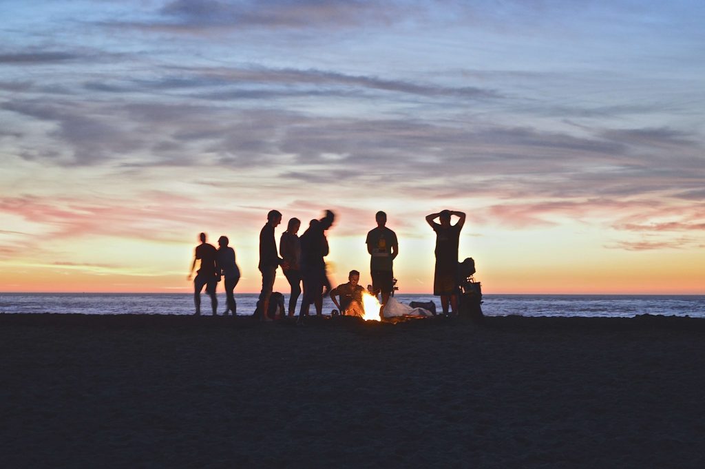 people sitting by the fire on the beach 