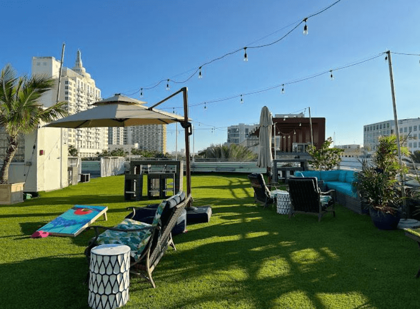 a city rooftop with chairs, sunbeds, and lawn games