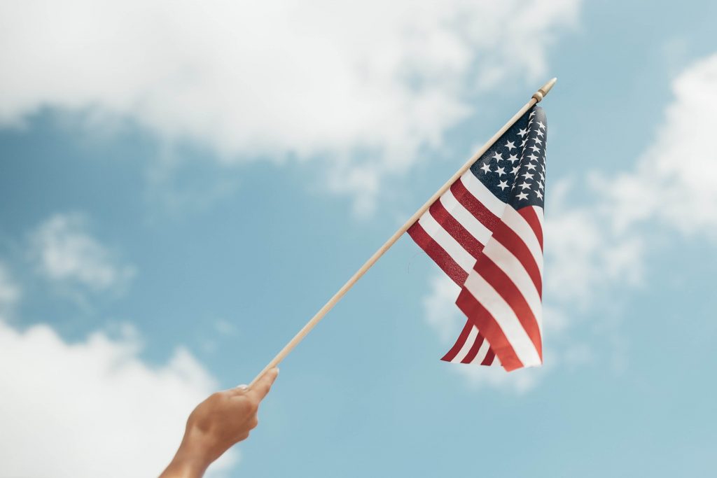 a hand waving an American flag to the sky 