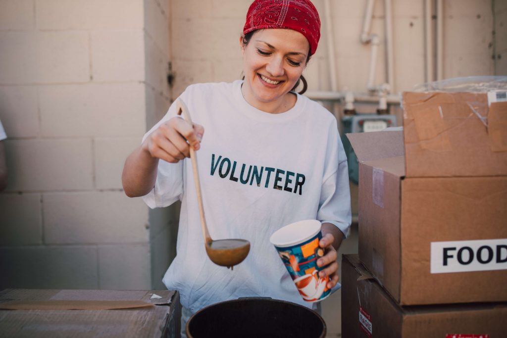 Volunteer smiling as she pours soup