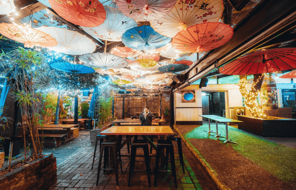 A bar venue decorated with colourful umbrellas and string lights