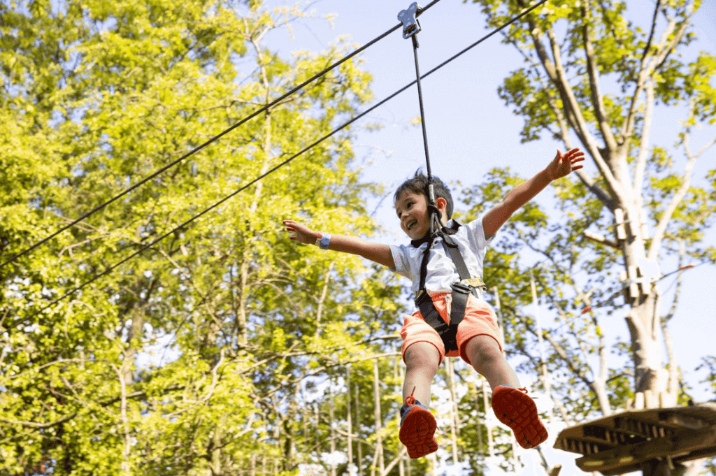 a kid smiling riding down a zip line
