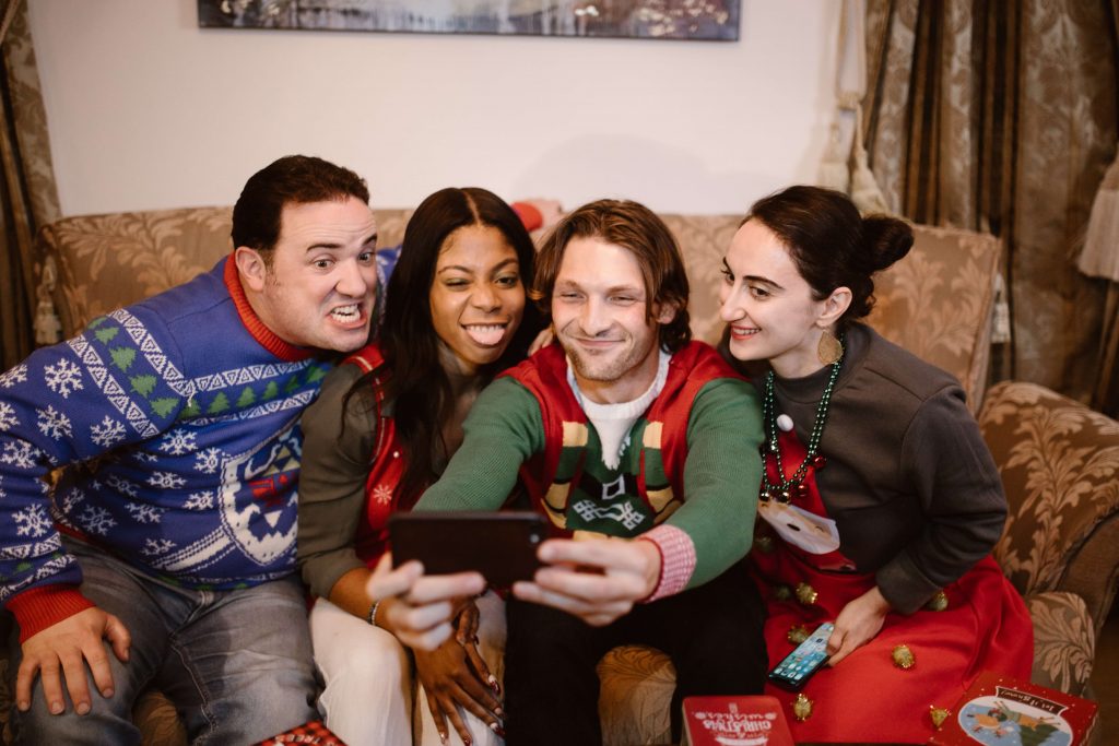 A group of people dressed in ugly Christmas sweaters taking a selfie