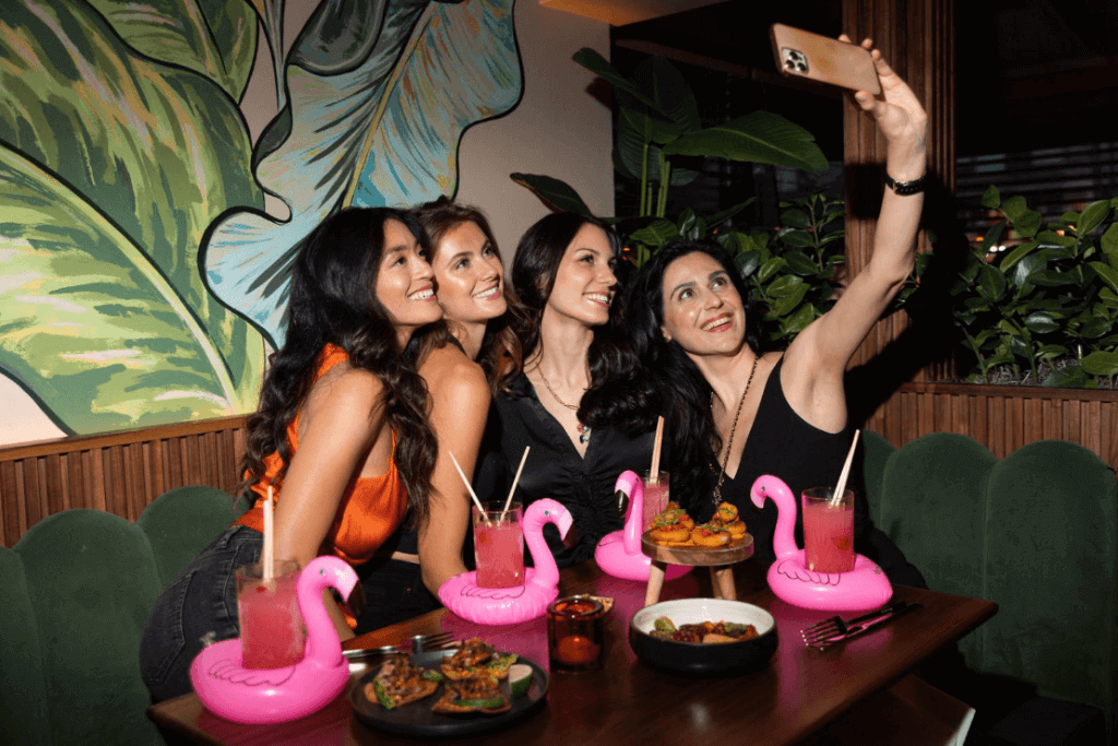 A group of young women talking a selfie in a tropical-themed venue