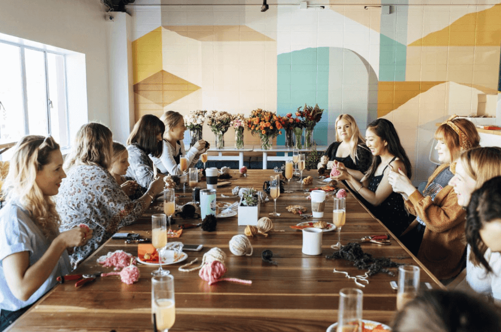 A group of women sitting at the table working on a craft together