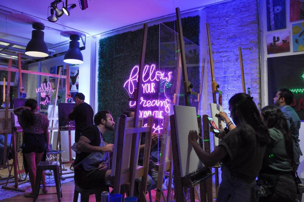 people sitting at easels in dark-lit room