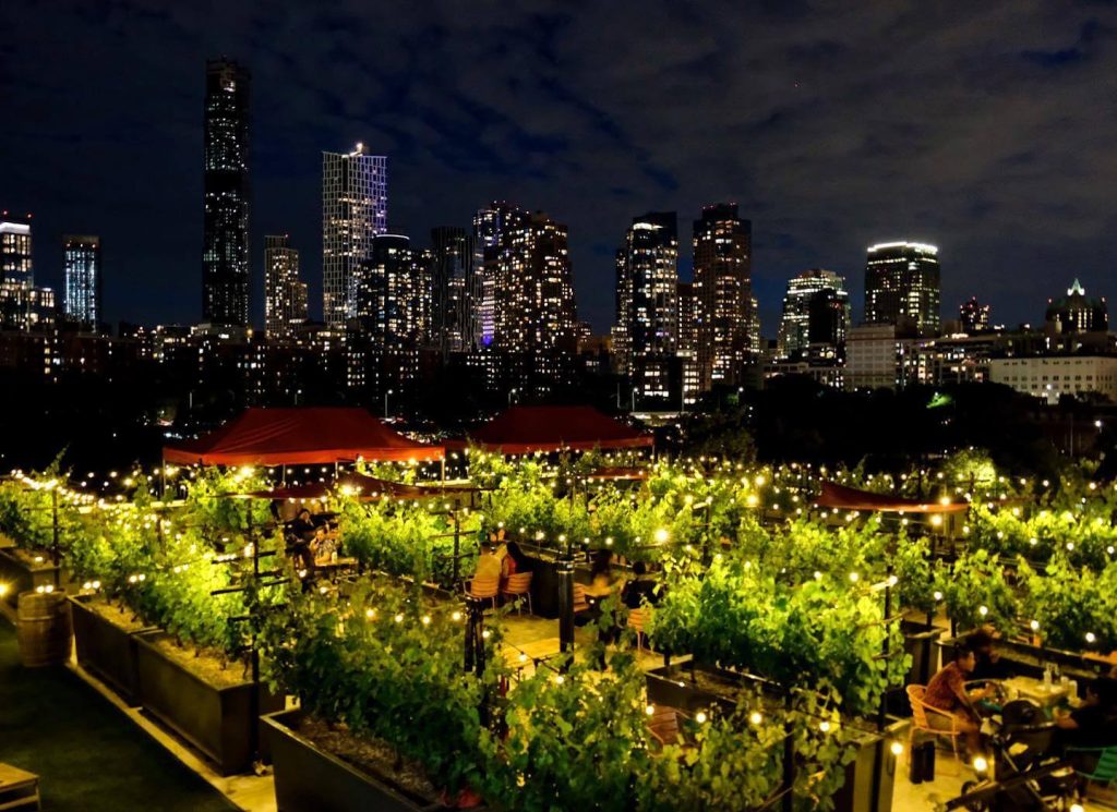 a rooftop venue with a view of a nighttime NYC skyline