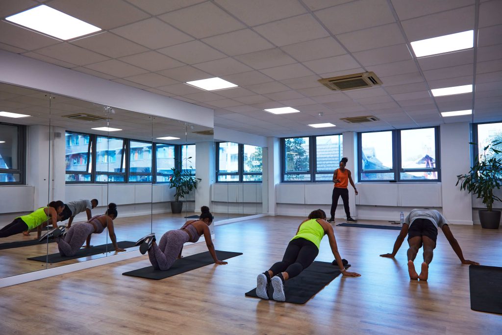 Bright fitness studio with large mirrors, wooden flooring, and a group engaging in a pilates class, suited for a health-conscious birthday activity.