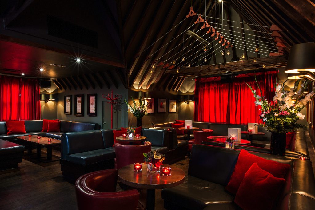 Luxurious champagne bar with opulent decor, red velvet seating, and striking chandeliers, offering an elegant backdrop for a birthday toast.