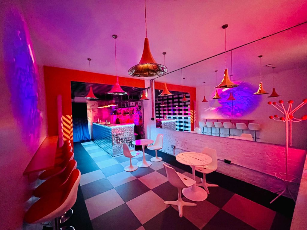 Eclectic bar interior with vibrant colours, modernistic furniture, and playful lighting creating a whimsical ambiance for a fun birthday party.