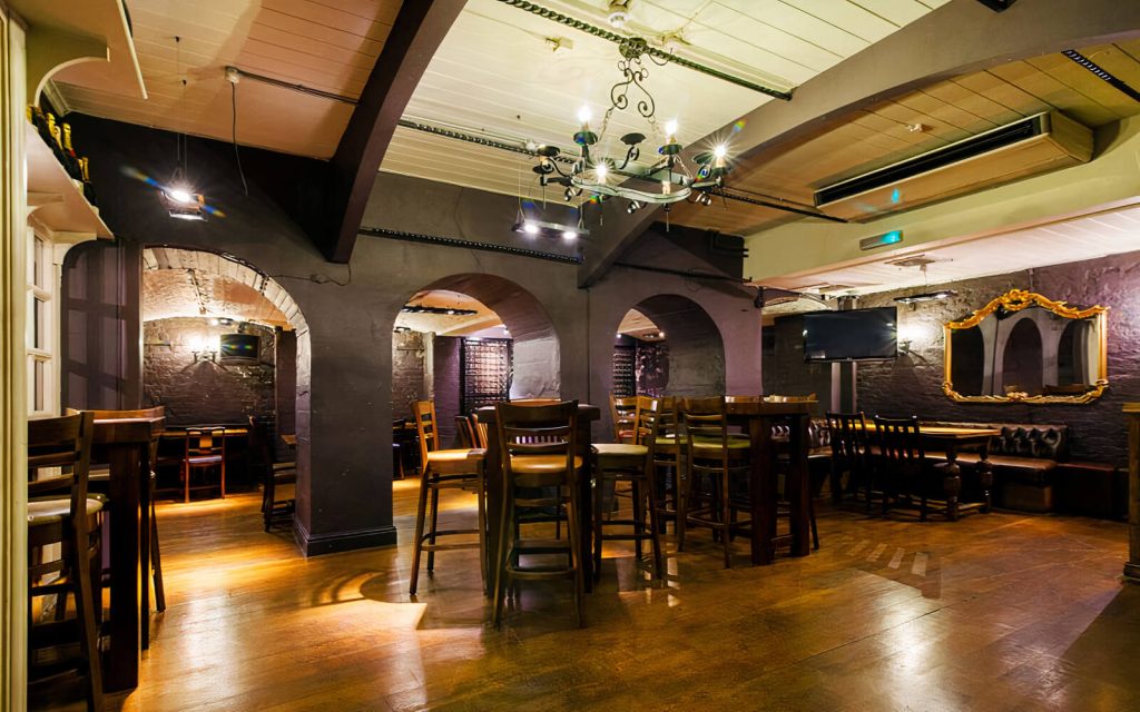 Rustic cellar bar with warm wooden furnishings and cosy nooks, providing a traditional British pub atmosphere for a birthday gathering.