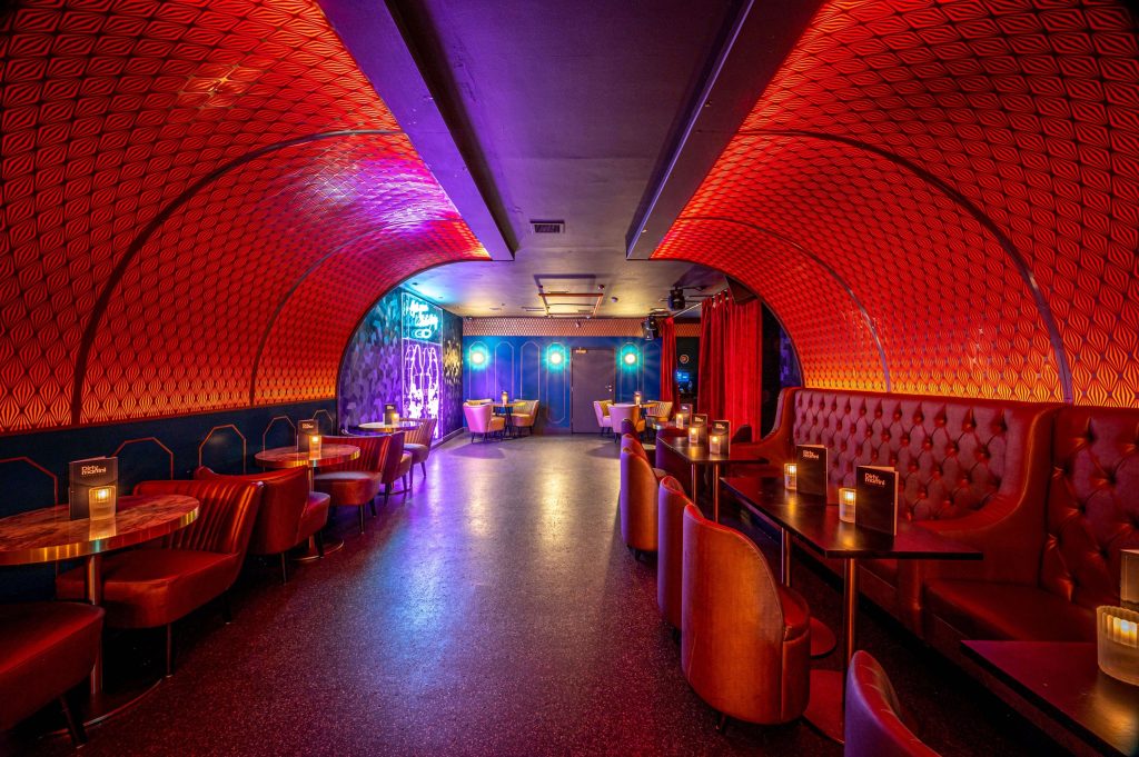 Futuristic lounge area with red geometric patterns, plush red booths, and moody lighting creating a vibrant space for a lively birthday party.