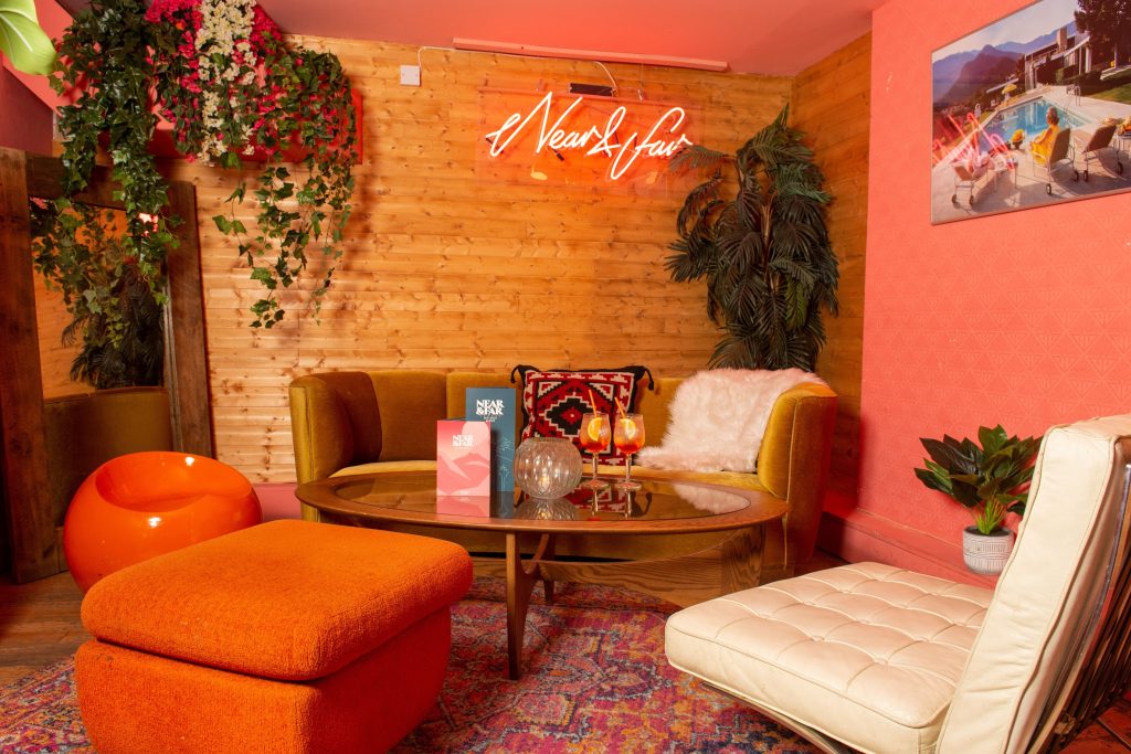 Retro-inspired lounge with neon signage, colourful plush seating, and eclectic decor for a funky and cheerful birthday celebration.