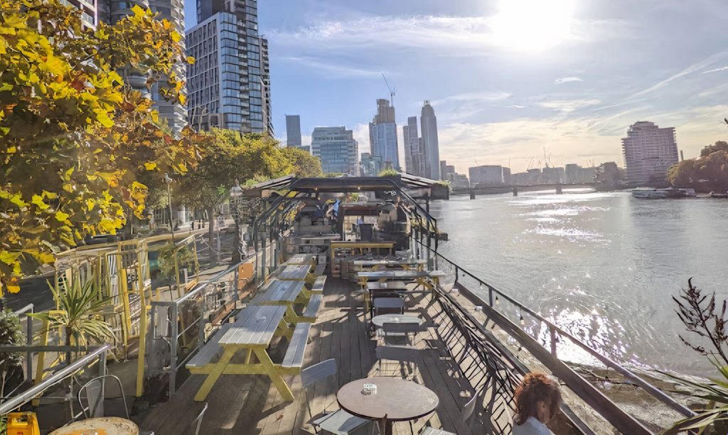 Riverside bar deck with panoramic views of the river, casual outdoor seating, and a laid-back atmosphere for a birthday celebration with a view.