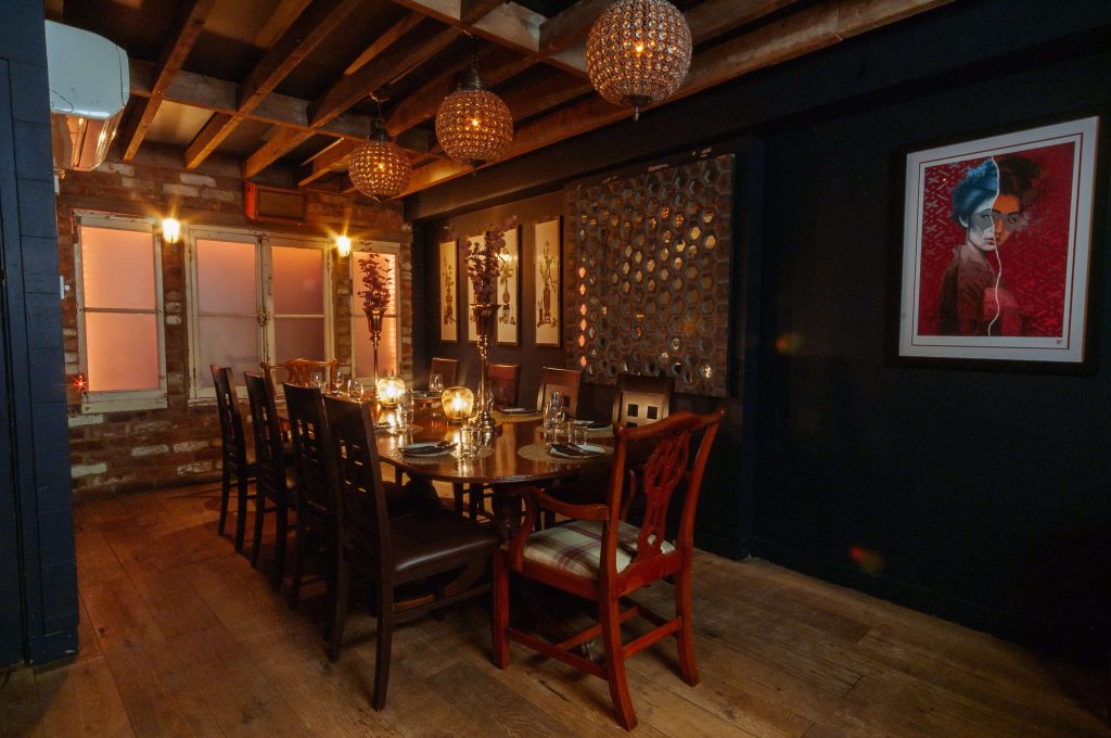 Rustic and atmospheric private dining room with exposed brickwork, unique pendant lighting, and cosy wooden furniture for an intimate birthday celebration.