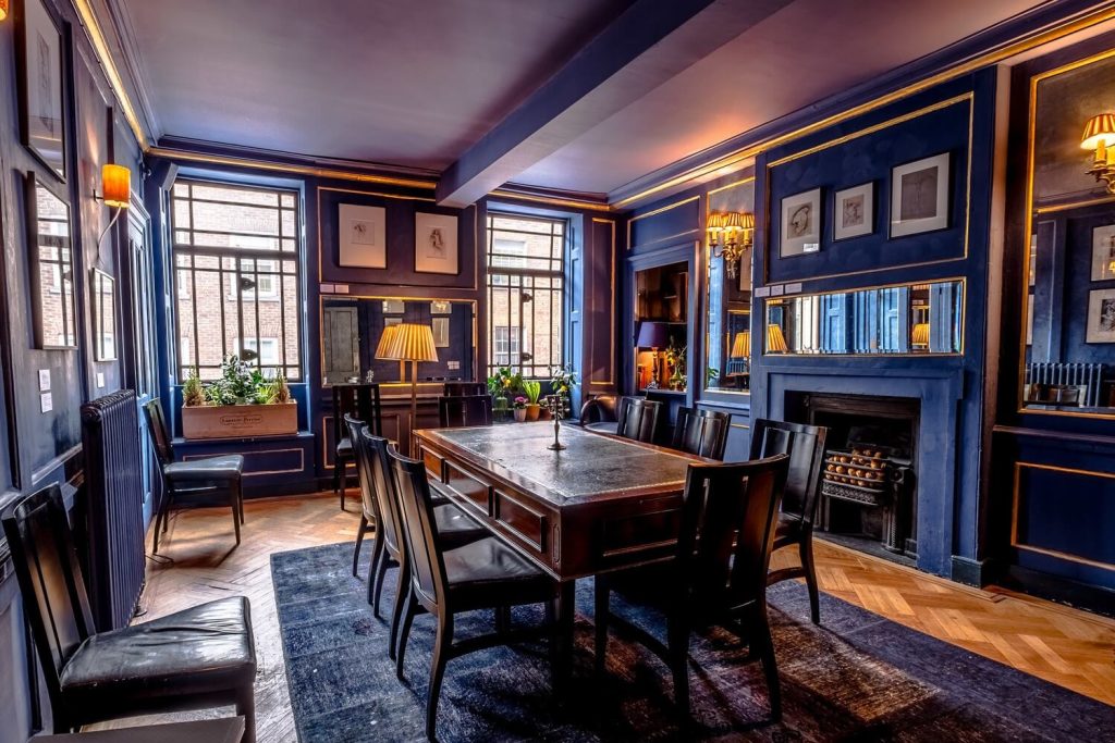 Refined drawing room with deep blue walls, stately art pieces, and vintage furnishings providing a regal setting for a birthday celebration.