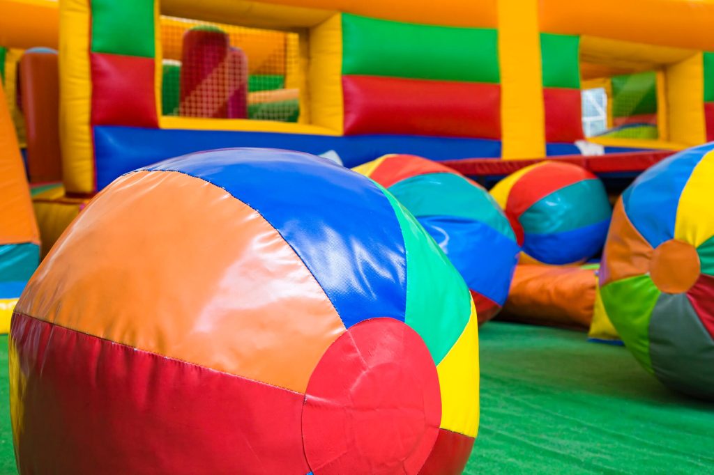 A colorful indoor play area with large inflatable balls and structures for children to play on, promoting an active and fun environment for a birthday party.