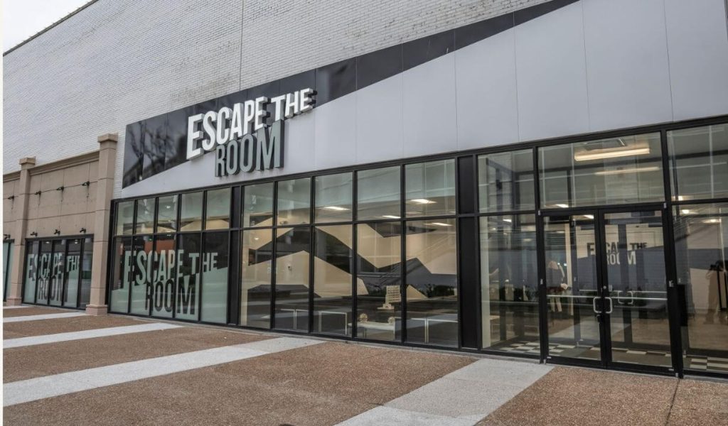 An 'Escape the Room' venue with a large storefront, featuring clear glass windows and a bold sign above, suggesting an interactive group entertainment experience.