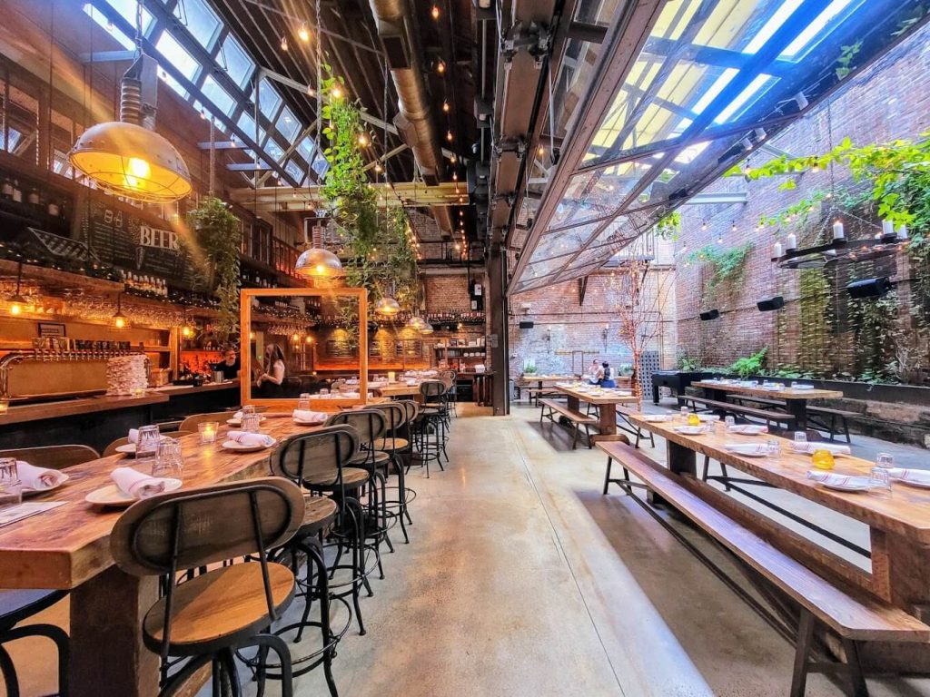A spacious brewery with an industrial aesthetic, long communal tables, and a vibrant atmosphere.