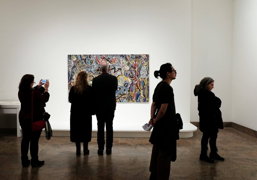 People looking at paintings in a museum space.