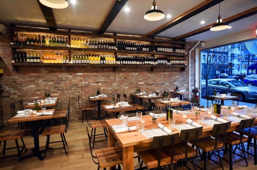 Rustic and charming main dining area with exposed brick walls and wooden tables, prepared for a birthday gathering in Soho, NYC.