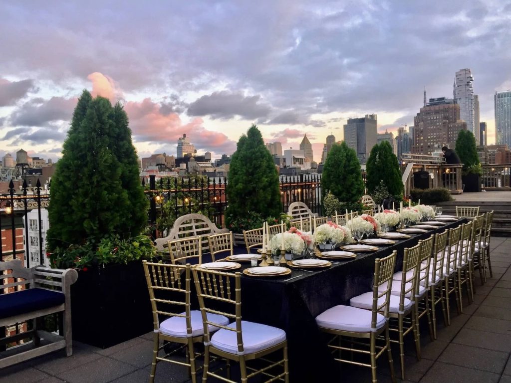 Rooftop event space elegantly set for a birthday dinner with skyline views at dusk in New York City.