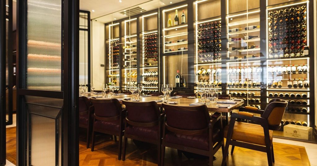 Sophisticated private dining room with a wine display, plush seating, and ambient lighting for an intimate birthday celebration.
