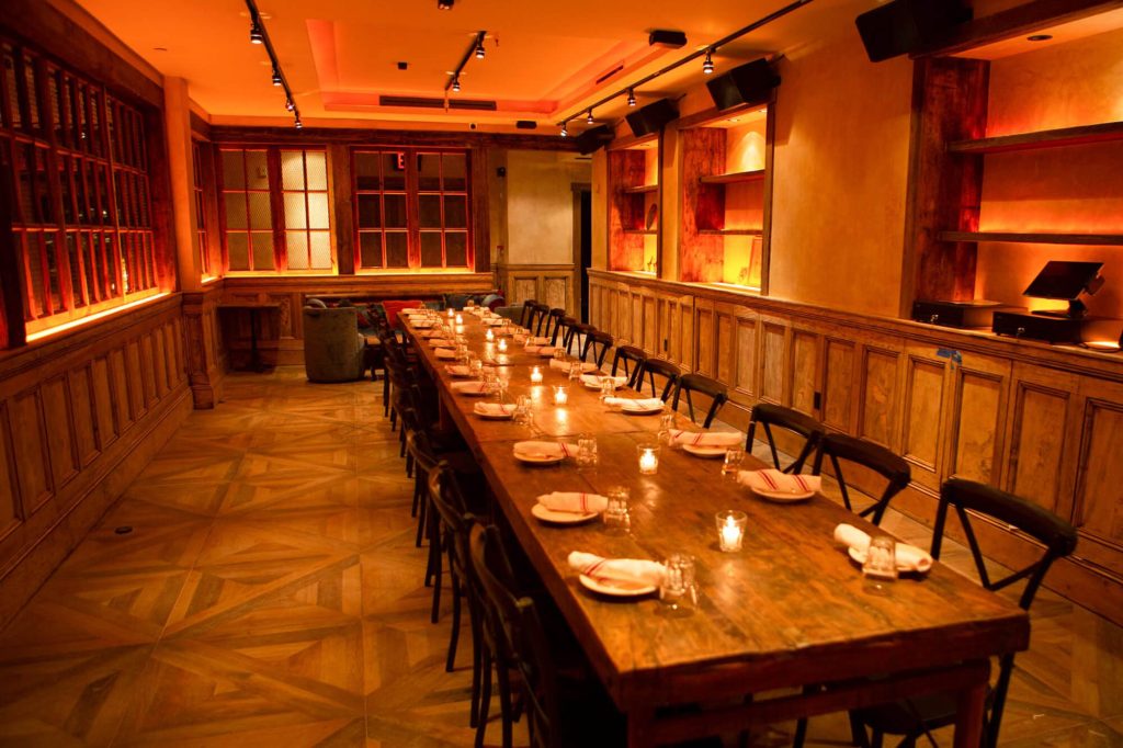 A warm and inviting private dining space at Ainslie Bowery with a long wooden table and intimate lighting.