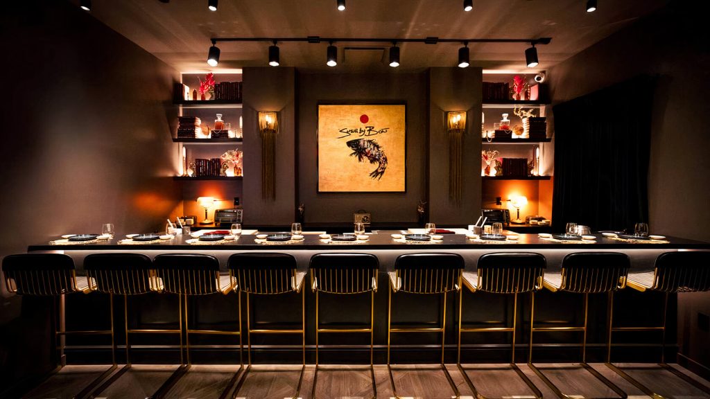 An upscale sushi bar at Sushi by Bou in Chelsea, NYC, with modern bar stools and striking artwork on the wall.