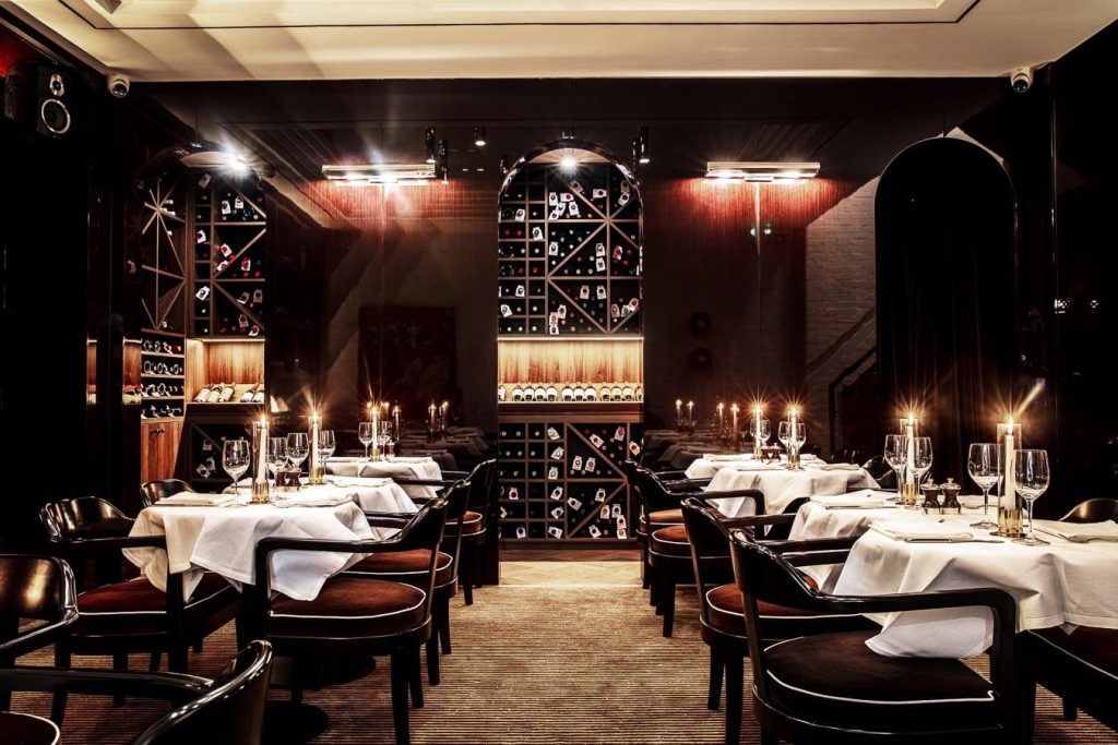 An elegant restaurant setting with candlelit tables, a wine rack wall feature, and plush seating, offering a romantic and sophisticated dining experience.