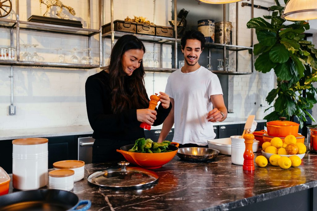 two people smiling and cooking together in brightly lit kitchen