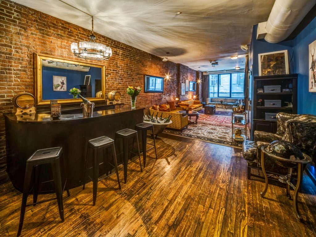 A cozy dinner party venue in NYC with exposed brick walls, a wooden bar, and a homey, vintage-inspired lounge area.