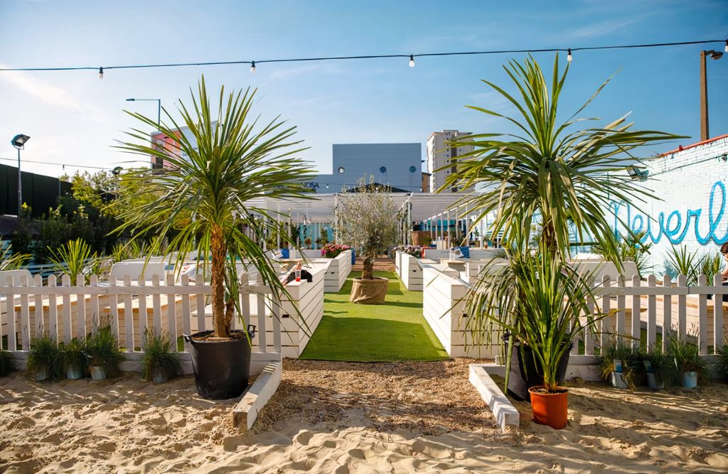 Sunny beach setting in London with palm trees and sand, ideal for unique summer party venues in the city.