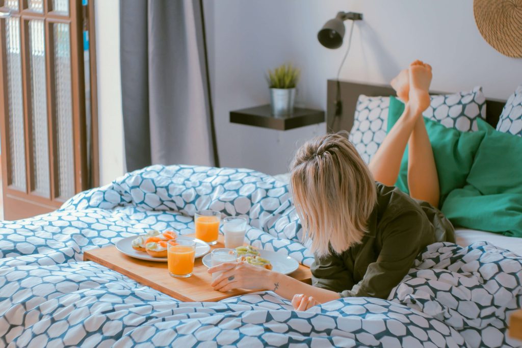 A woman laying on a bad and eating breakfast.