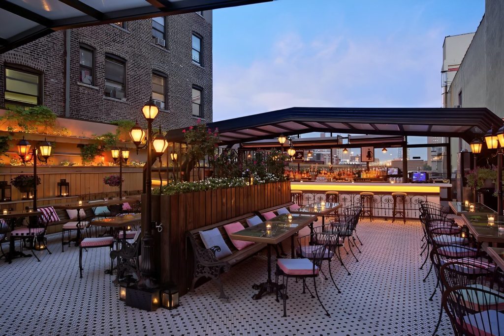 An elegant rooftop bar with cozy seating, ambient lighting, and a view of the cityscape.